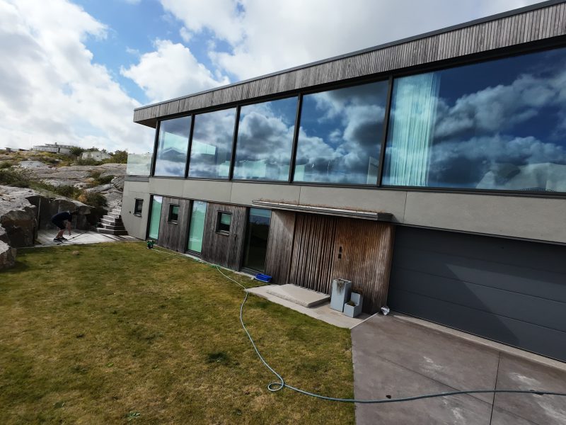 Villa med stora glaspartier och utrustning på gräsmattan