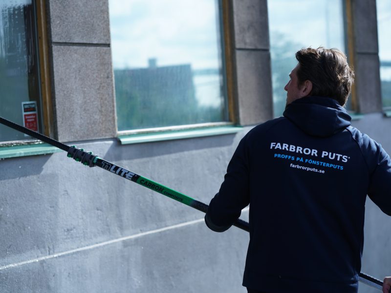 Farbror Puts arbetar med teleskopskaft vid ett skyltfönster