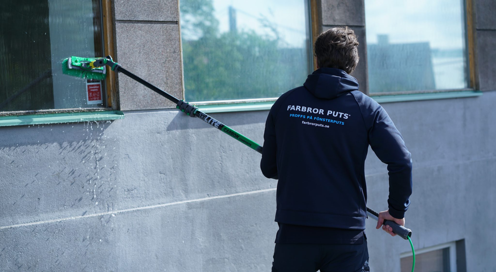 Farbror Puts rengör ett stort skyltfönster från marken